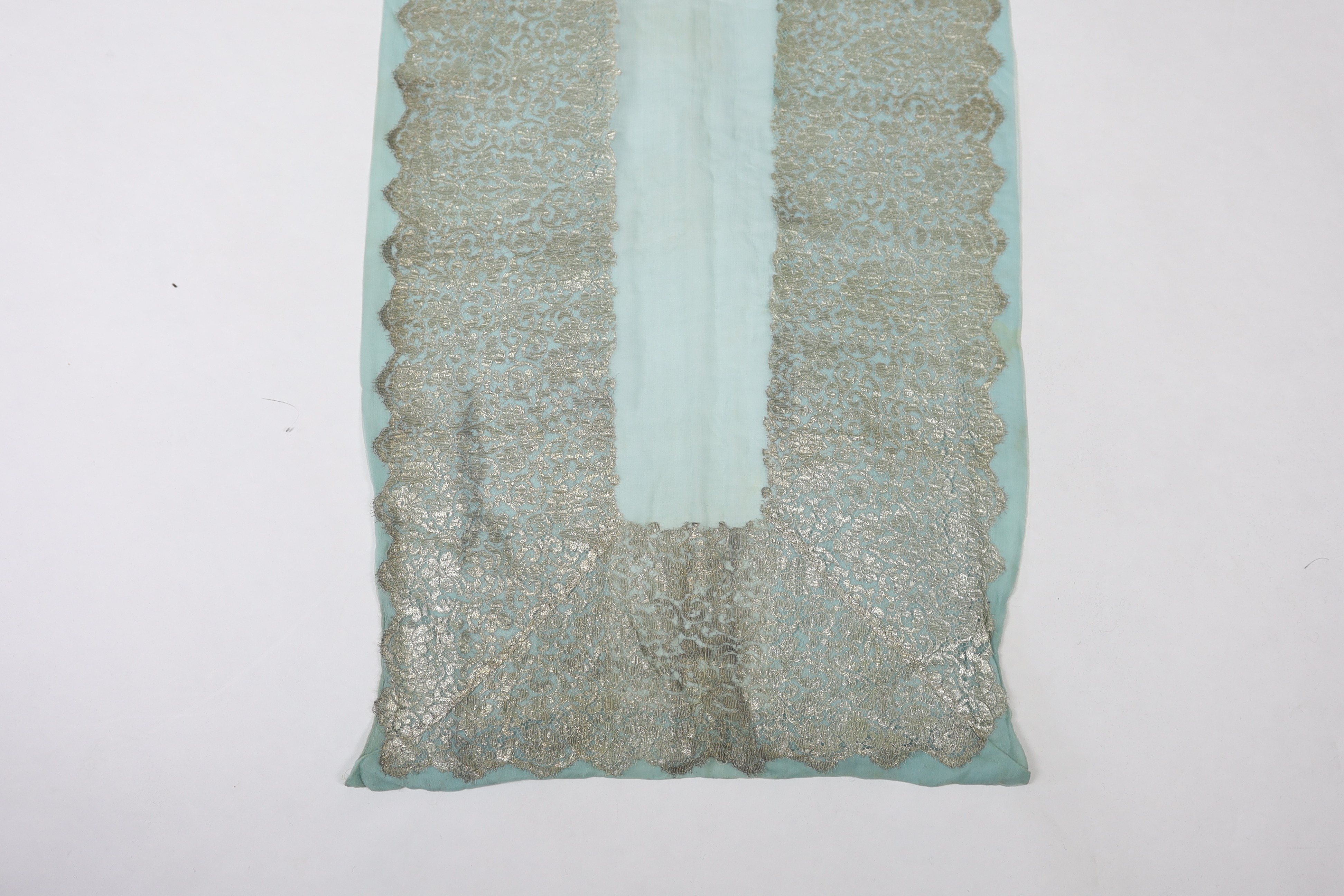 A 1920's silver machine lace and chiffon train, to an evening dress, the silver lace has been cut and appliquéd onto the turquoise chiffon, 209cm long